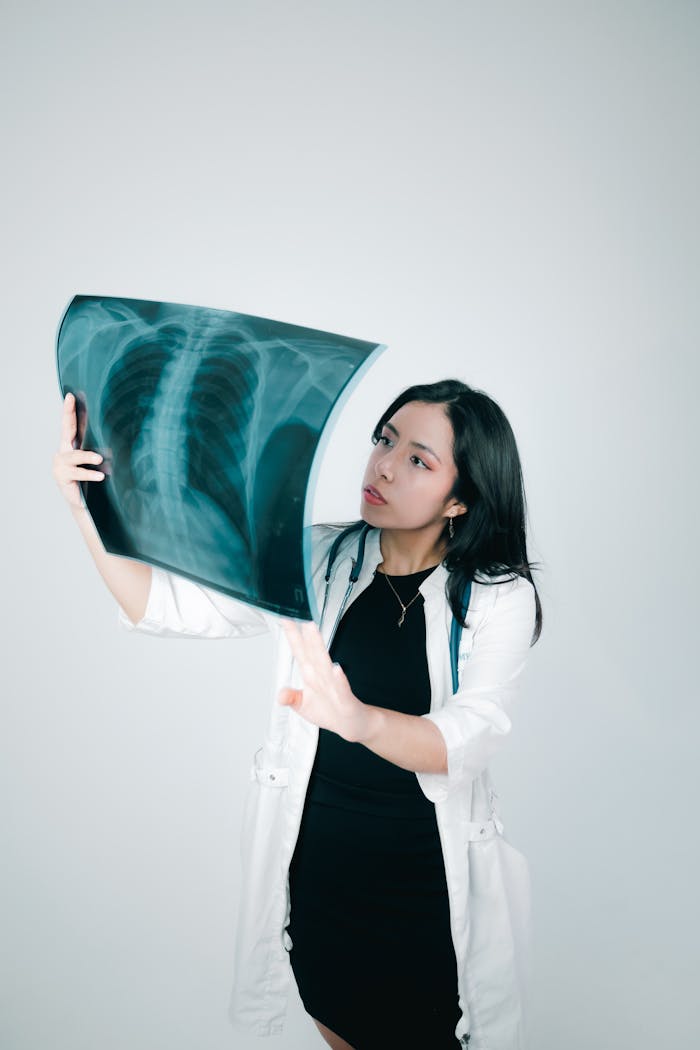 Female doctor carefully analyzing a chest X-ray indoors, highlighting medical diagnosis and healthcare practice.